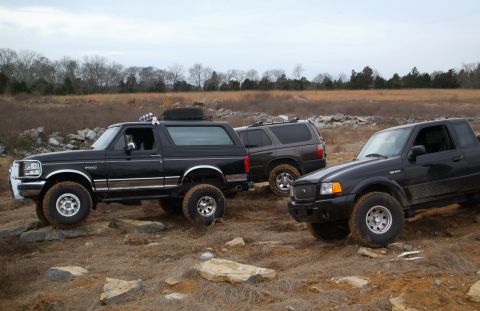 1995 Ford Bronco - A black 1995 Ford Bronco navigates a rocky trail alongside two other off-road vehicles.