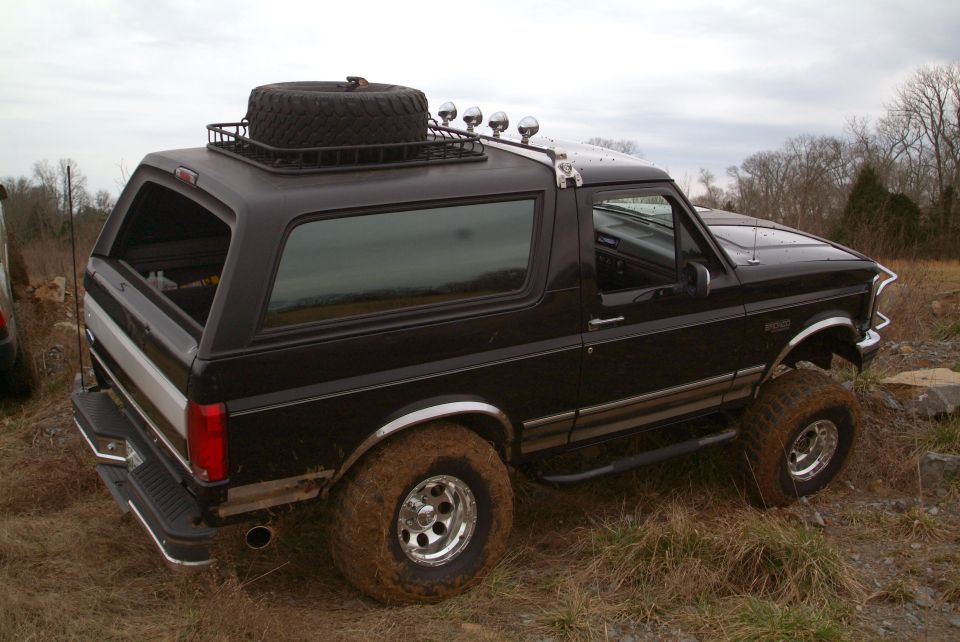Black lifted Ford Bronco rear three-quarter view with roof rack spare tire