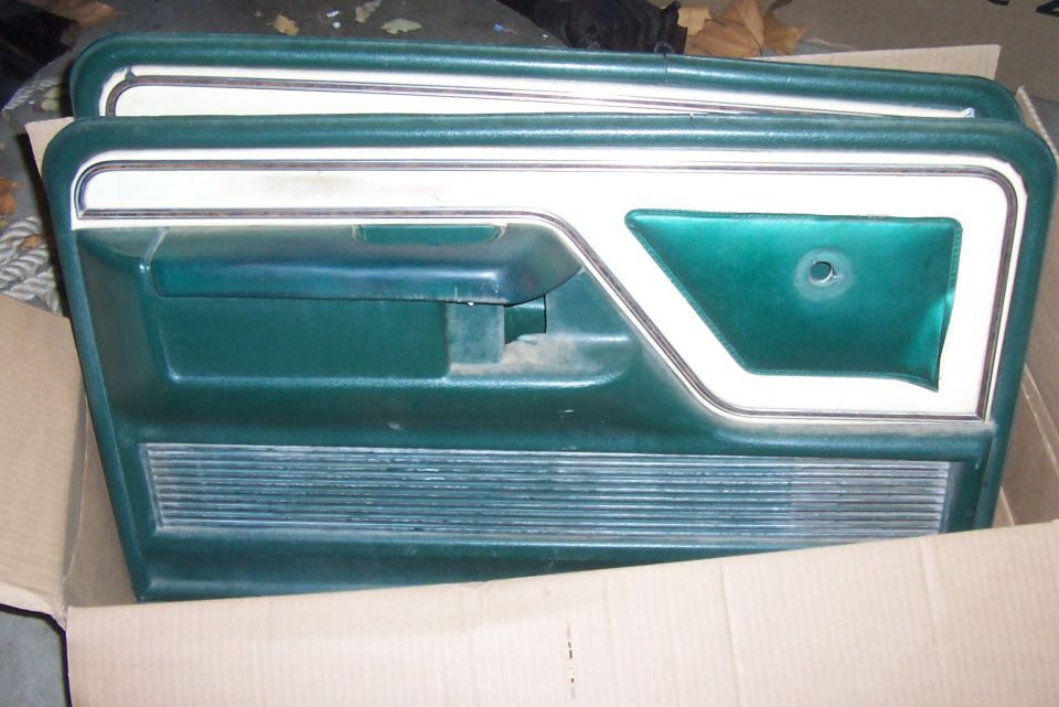 Teal green truck door panel with chrome trim laid in a cardboard box