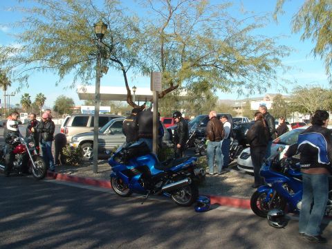 2007 Kawasaki Ninja - A group of motorcyclists gathered with their bikes in a parking lot on a sunny day.