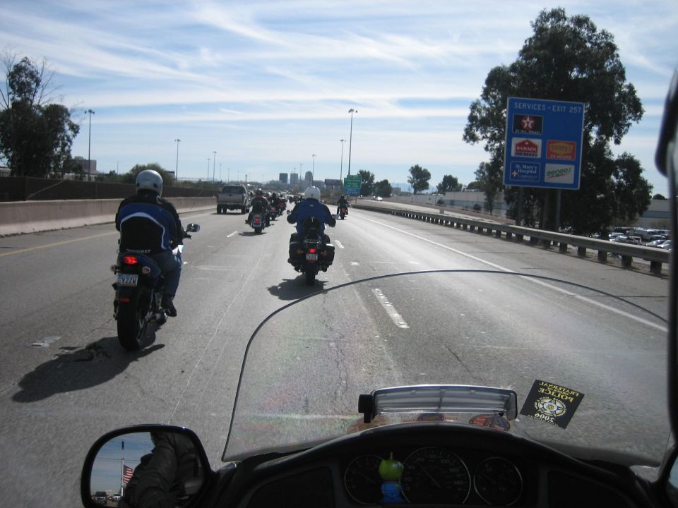 Riding in a group on the highway, with a few bikes ahead and cars in the distance. Services exit sign visible