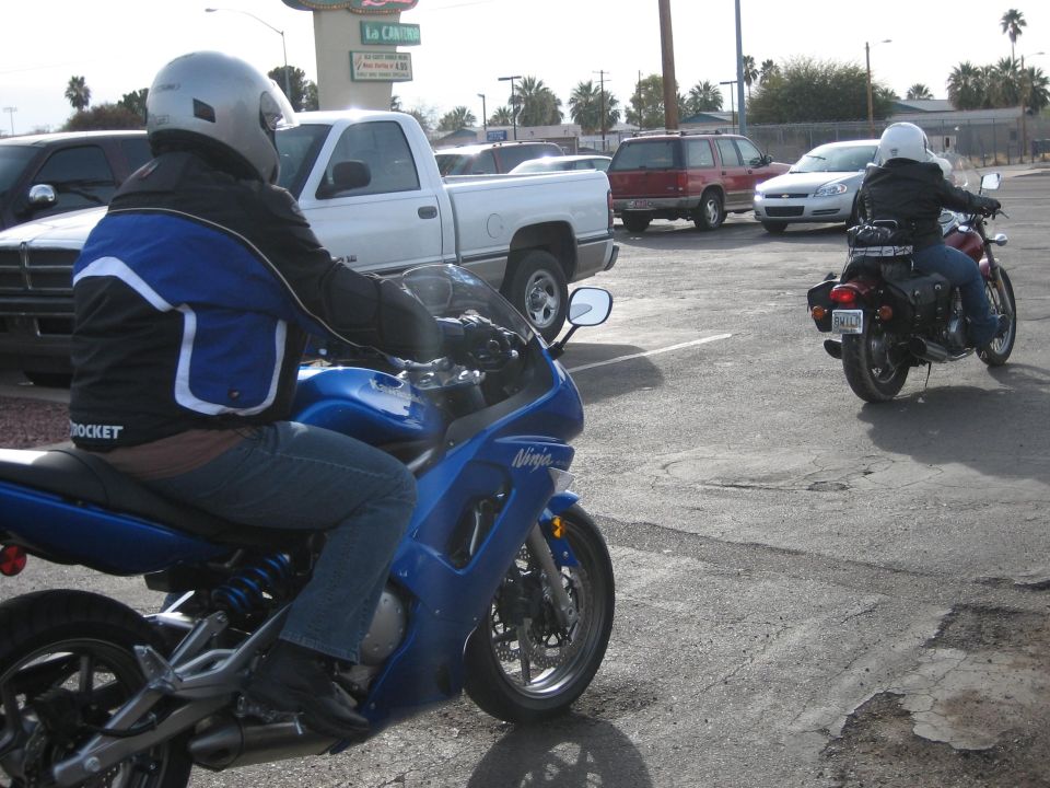 Blue Kawasaki Ninja sportbike with rider, another motorcycle in background