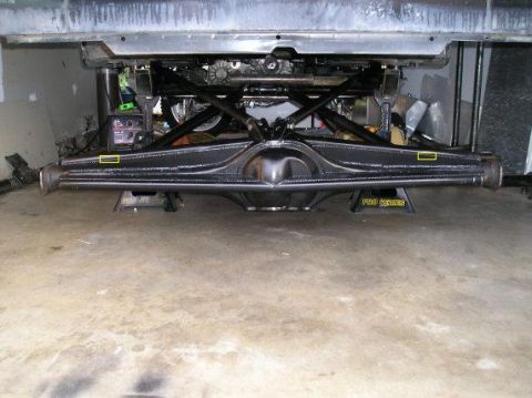 1987 Jeep Cherokee - Underside view of a vehicle's rear axle assembly, supported by jack stands in a garage.