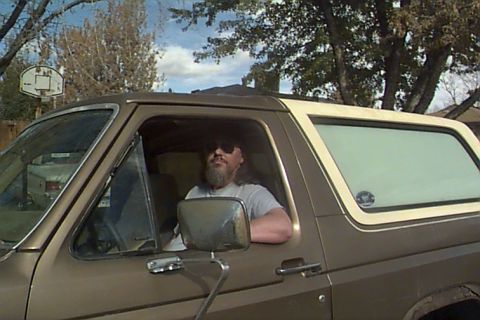 1980 Ford Bronco - A man sits in the driver's seat of a brown Ford Bronco, looking out the window.