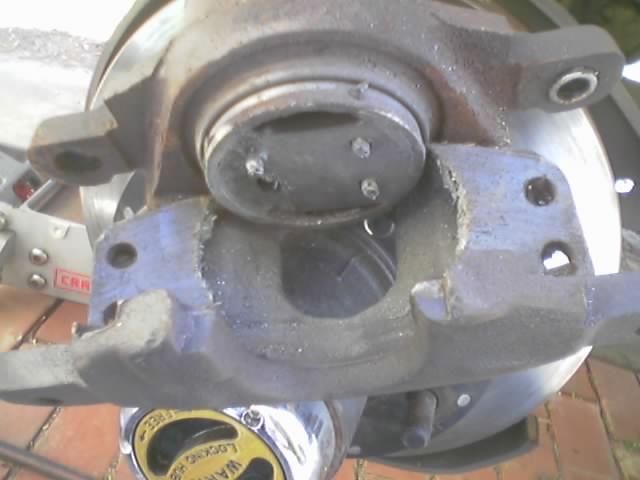 Rusty front disc brake, hub and steering knuckle disassembled on brick pavers