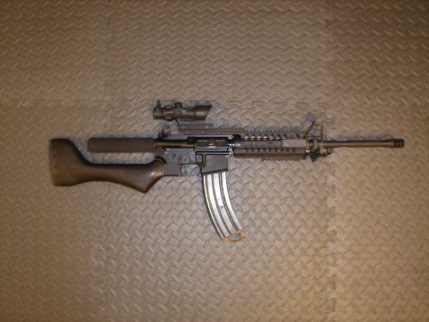 1990 Ford Bronco - Assault rifle with scope and extended magazine is shown on a textured background.