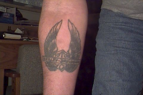 1980 Ford Bronco - A tattoo of a winged shield emblem is visible on an arm, next to denim jeans.