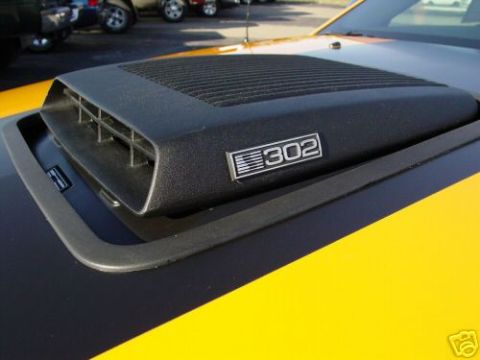2007 Saleen S-302 - A black hood scoop with a "302" emblem is visible on the hood of a yellow car.