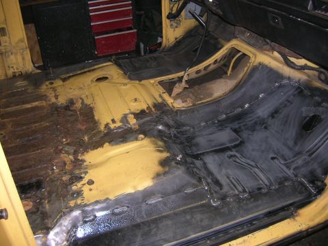 1982 Ford Bronco - The interior floor pan of a vehicle shows extensive rust damage and recent welding repairs.
