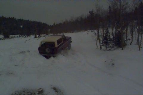 1980 Ford Bronco - A 1980 Ford Bronco navigates a snowy landscape, kicking up snow as it drives.