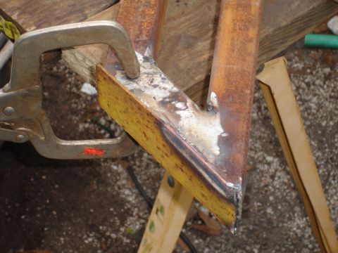 1989 Ford Bronco - A close-up view of metal parts being prepared for welding, held by a clamp.