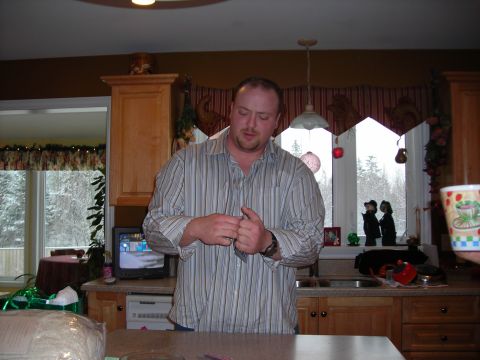 1984 Ford Bronco - A man stands in a kitchen, preparing to button his shirt.