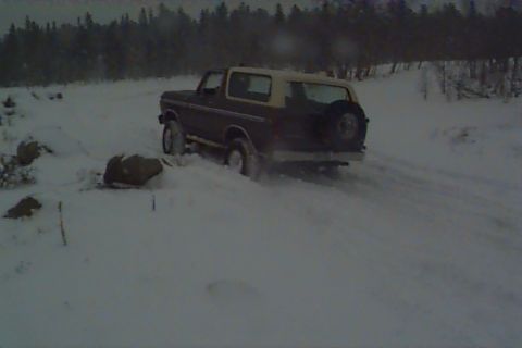 1980 Ford Bronco - A Ford Bronco navigates a snowy landscape with a spare tire mounted on the back.