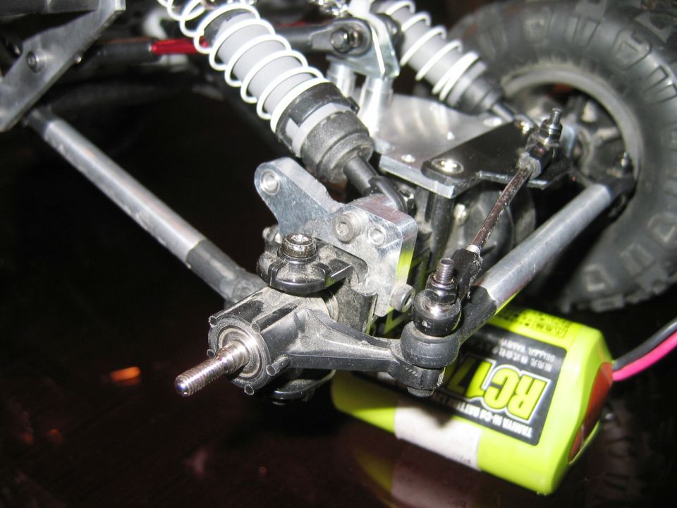 Close-up of RC car front suspension, shock, steering knuckle and yellow battery pack