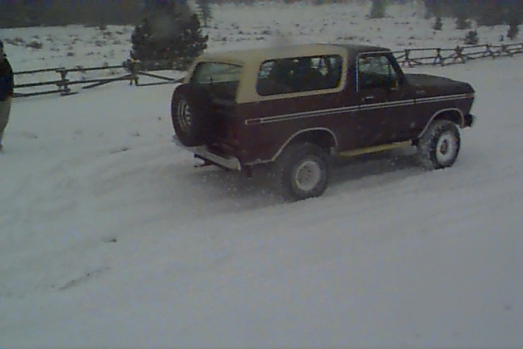 Maroon and tan 1980 Ford Bronco in snow, rear quarter view
