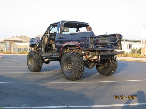 1994 Ford Bronco - This heavily modified SUV, likely from the 1980s, has been stripped down and equipped with off-road tires.