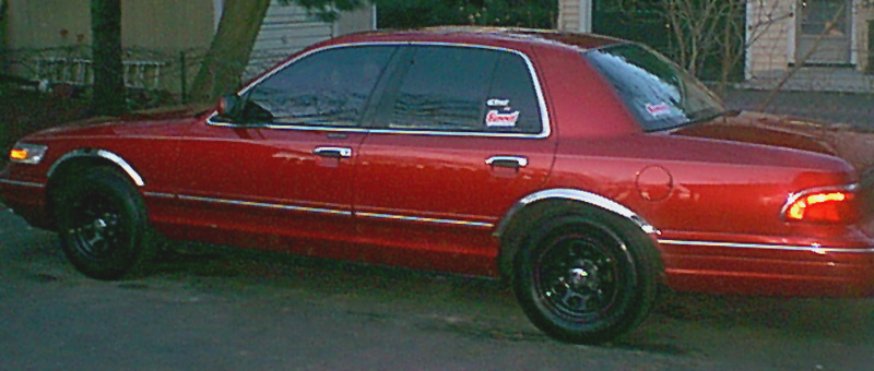 Dark red four-door sedan, driver-side profile view, with black steel wheels parked outdoors.