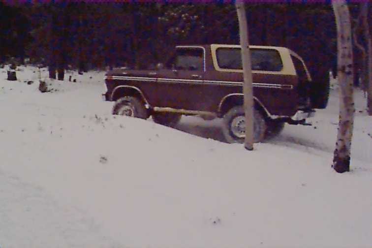 Brown 1978 Ford Bronco with tan top driving through snow
