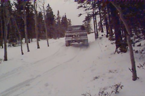 1980 Ford Bronco - A pickup truck navigates a snow-covered trail surrounded by a forest.