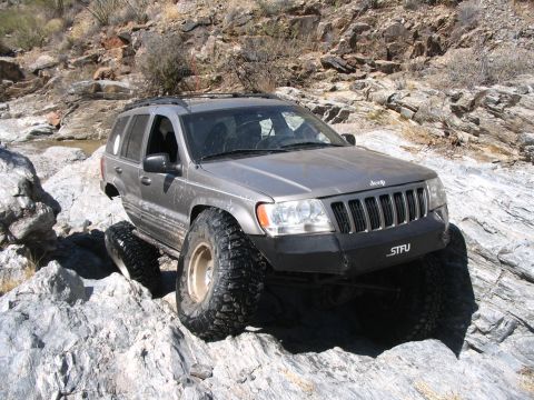 1999 Jeep Grand Cherokee - This 1999 Jeep Grand Cherokee navigates a challenging rocky trail with its large off-road tires.