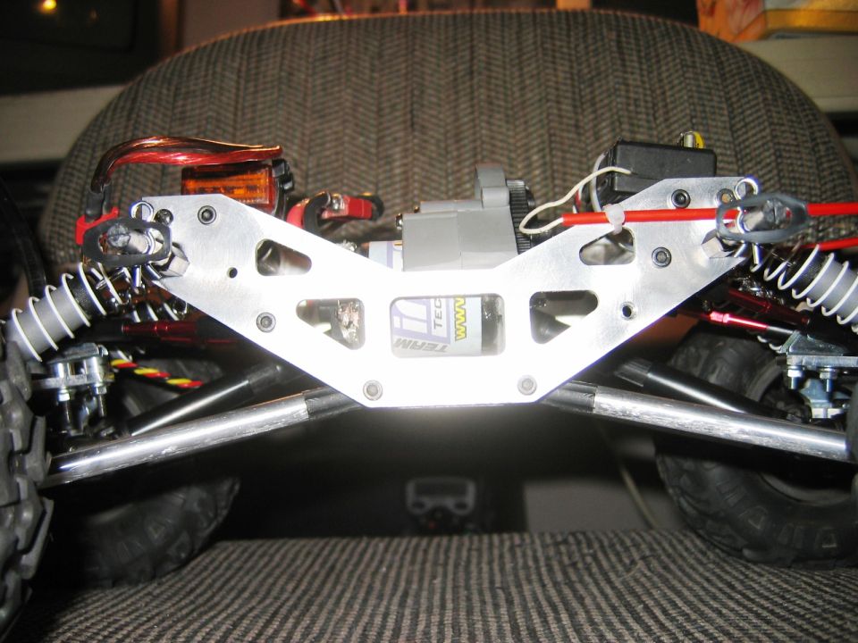 RC car front chassis with aluminum plate, shocks, motor and battery on fabric surface