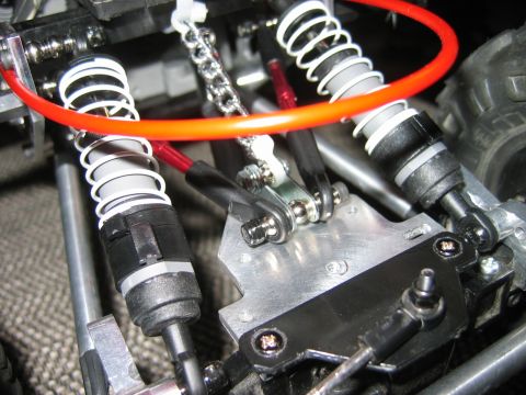 1985 Ford Bronco - Detail shot of the suspension system on a remote-controlled vehicle, showing shocks and metal linkages.