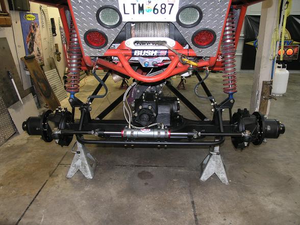 Custom off-road vehicle chassis on jack stands, showing suspension and drivetrain components