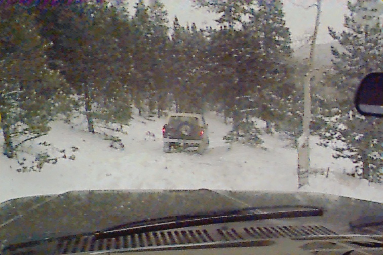 Rear view of tan SUV in snow, with another vehicle visible ahead