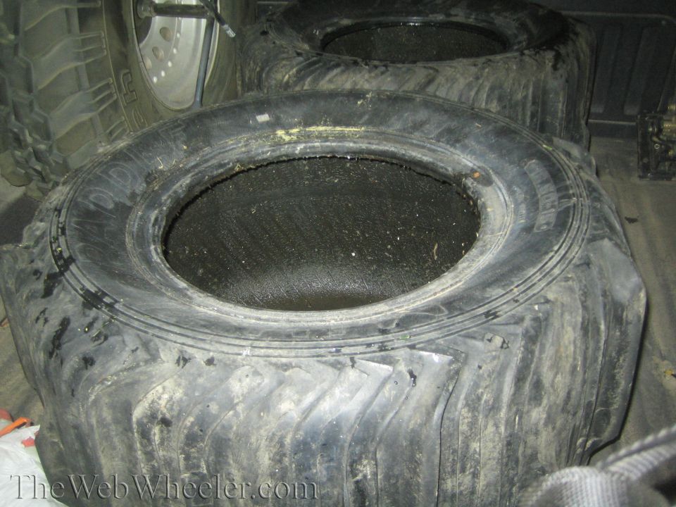 Two large paddle tires in a vehicle bed, one with visible text