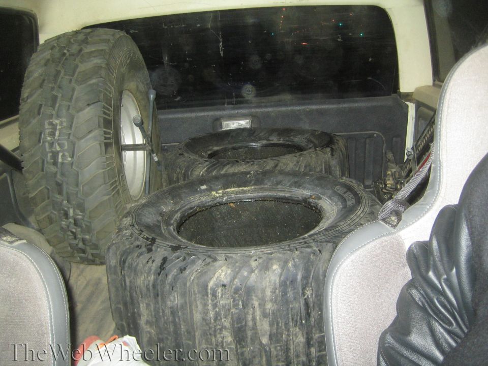 Spare tires stacked inside a vehicle with gray seats visible