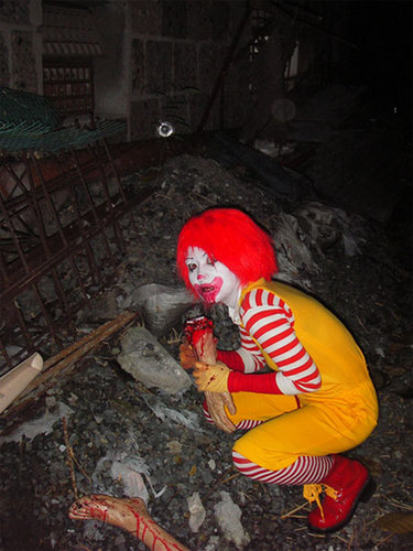 1987 Suzuki Samurai - A person dressed as a clown is crouched in a pile of rubble, holding a bloody limb.