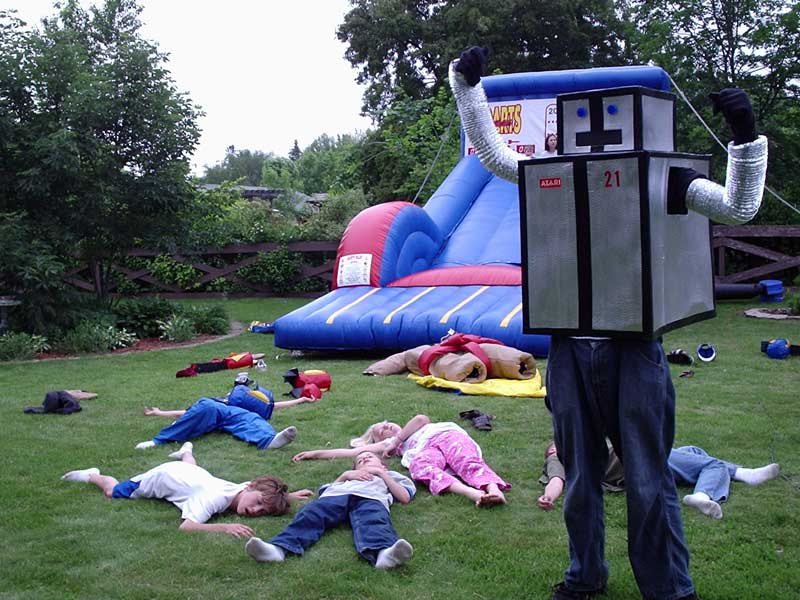 guy in robot costume, kids passed out on lawn, inflatable slide behind