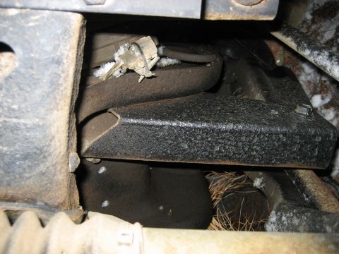 1990 Ford Bronco - Undercarriage view of a vehicle part, showing rust and some snow accumulation.