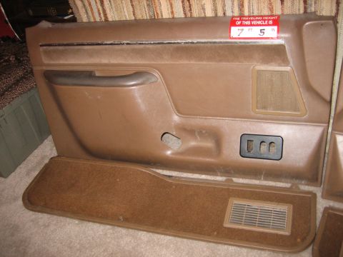 1990 Ford Bronco - Brown door panel with speaker grille and window crank hole, and a red sticker indicating vehicle height.