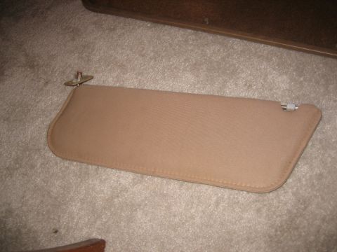 1990 Ford Bronco - A tan sun visor is shown lying on a carpeted surface.