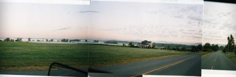 1989 Ford Bronco - View of a rural landscape with a road and a house, likely taken from a moving vehicle.