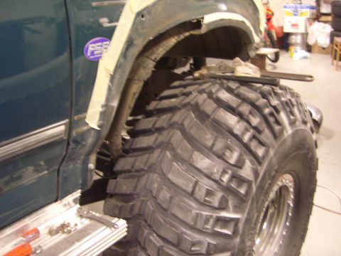 1996 Ford Bronco - A large, aggressive off-road tire is mounted on a vehicle undergoing modification.