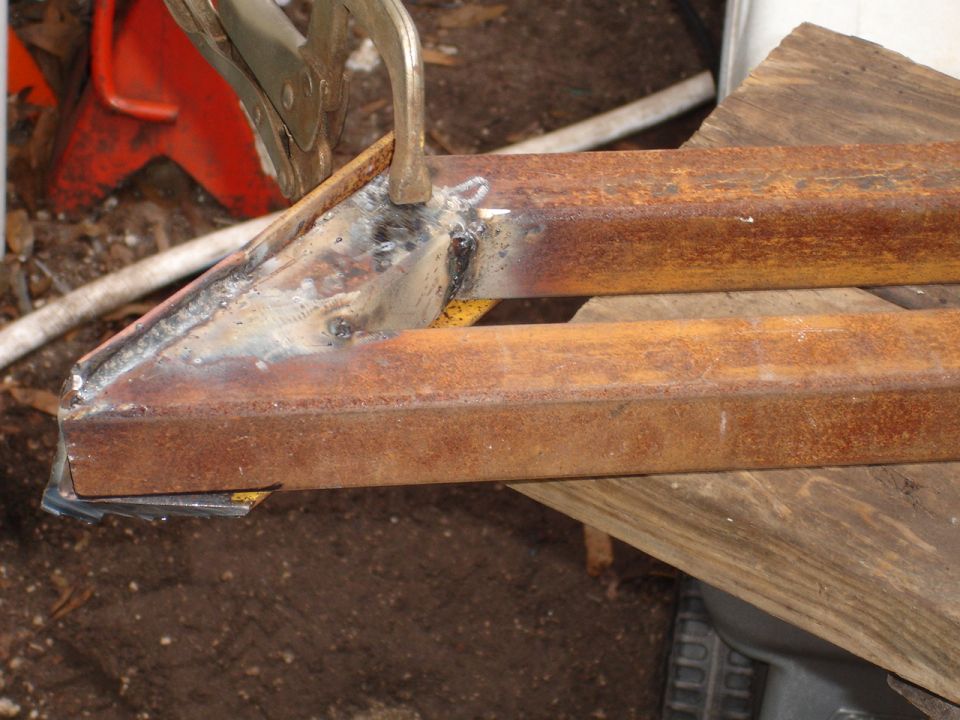 Metal tubes being welded together with a clamp holding them in place
