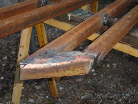 1989 Ford Bronco - Close-up of rusty metal sliders, likely aftermarket vehicle parts, resting on a sawhorse.
