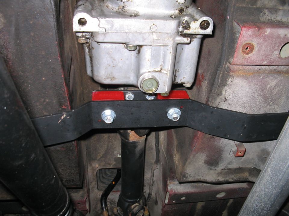 Underbody transmission crossmember: black tubular support bolted to a red frame