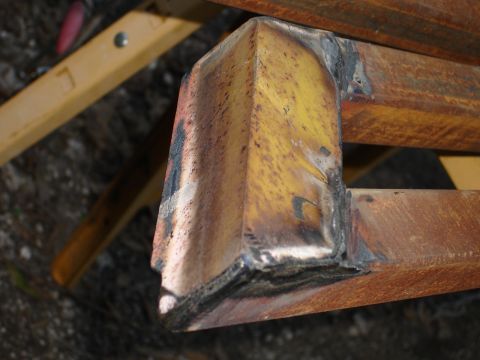 1989 Ford Bronco - Close-up view of a welded metal corner, showing signs of rust and yellow paint.