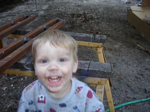 1989 Ford Bronco - Young child with a dirty face smiles for the camera, with wooden sawhorses and debris in the background.