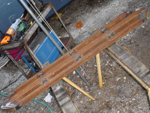 1989 Ford Bronco - A rusty metal slider part is shown resting on wooden supports, with tools and equipment in the background.