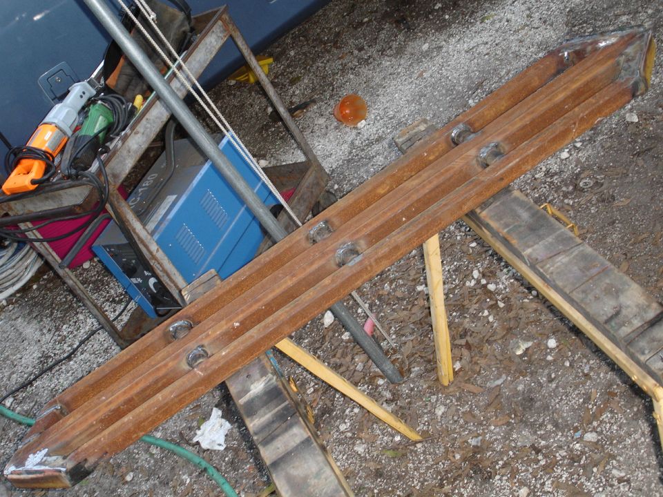 Rusty metal slider with three rows of circular indentations, resting on wooden supports