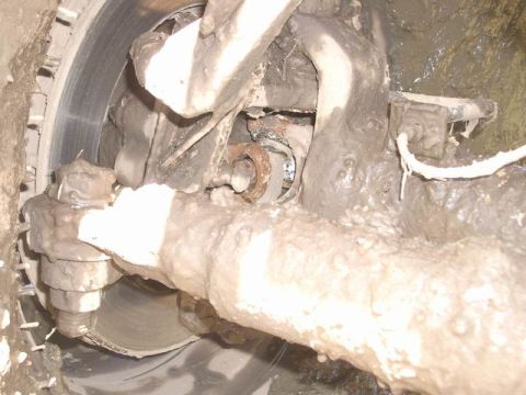 1995 Ford Bronco - This image shows heavily mud-caked suspension and brake components of a vehicle.