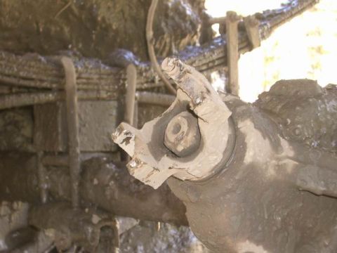 1995 Ford Bronco - This image shows a close-up of a heavily soiled suspension part, likely from a truck or SUV, with leaf springs in the background.