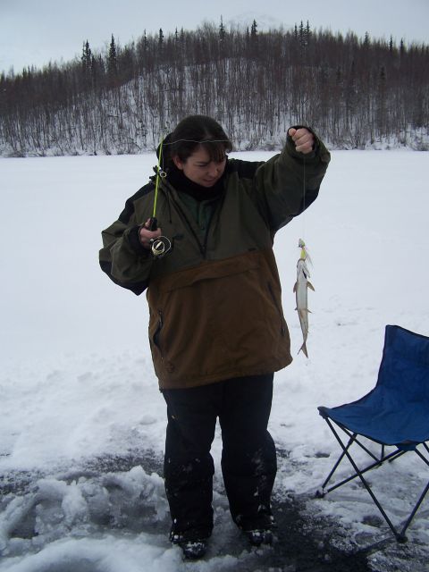 1979 Chevrolet Blazer - A person enjoys ice fishing on a frozen body of water with trees in the background.