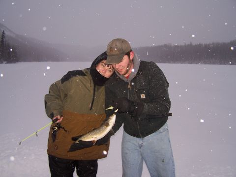 1979 Chevrolet Blazer - A couple poses with a freshly caught fish on a snowy day, with a frozen lake and distant trees visible.