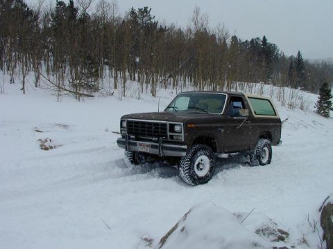1980 Ford Bronco - A brown 1980 Ford Bronco navigates a snowy landscape.