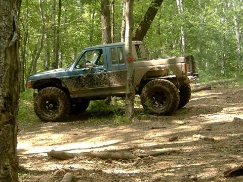 1988 Ford F-250 - This modified 1988 Ford F-250 navigates a wooded off-road trail, covered in mud from its adventure.